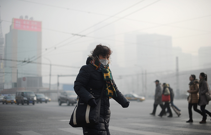 A woman wearing a face mask makes her way along a street in Beijing on January 16, 2014. (AFP Photo / Wang Zhao)